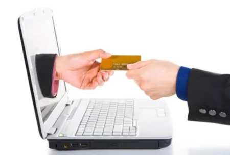 Main qui tend une carte bancaire à travers un écran