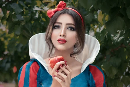 Une femme habillé en blanche neige avec une pomme rouge dans les mains