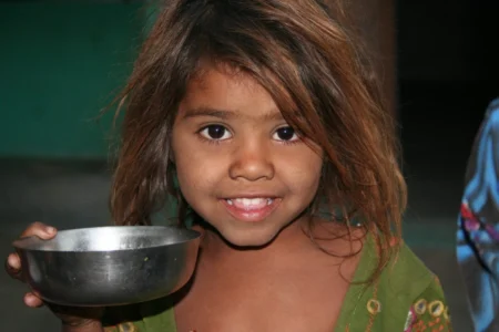 petite fille tunique vert tient bol nourriture argent