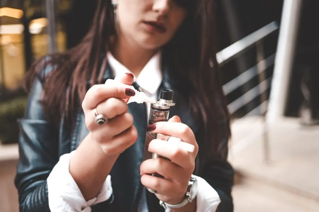 Femme qui met du e-liquide au CBD dans sa vapoteuse