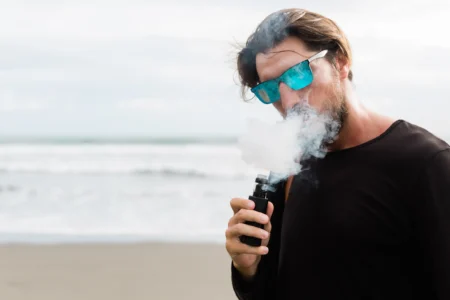 homme vapote cigarette électronique plage